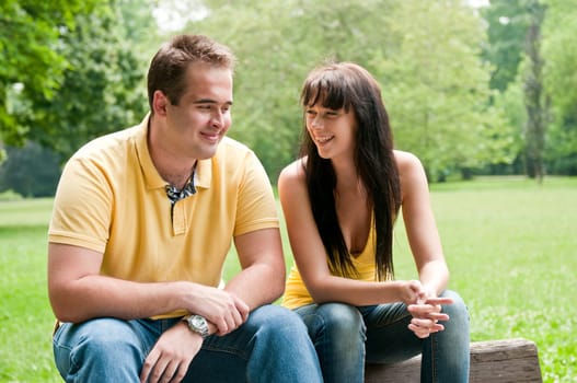 Young couple having great time - sitting on bench outdoors