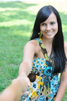 Young smiling woman stretching her hand and receiveing help