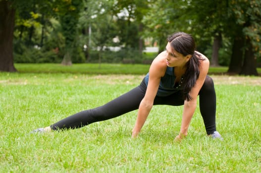 Woman performs stretching before sport in park