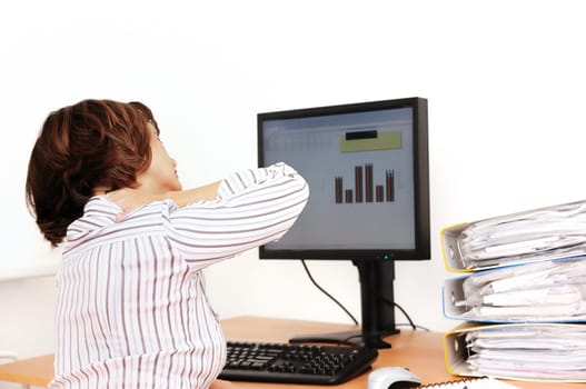 Business woman with neck pain sits on workplace with documents and monitor on table