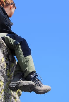Hiking woman relaxing on rocks with blue sky