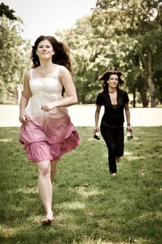 Two friends run barefoot in park on grass - freedom concept