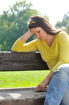 Portrait of worried teenager siting on bench in park