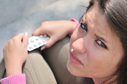 Young woman  (teenage girl) with anxious look holding tablets - above view