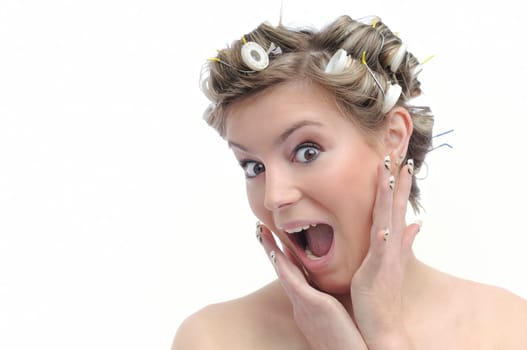 Young beautiful surprised woman with hair rollers in curls isolated on white