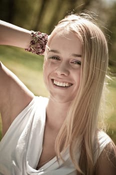 Warm tone outside portrait of young smiling woman - hand behind head