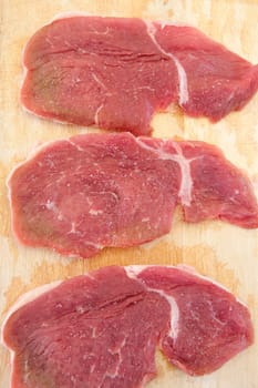 Three steaks raw salted pork on cutting board