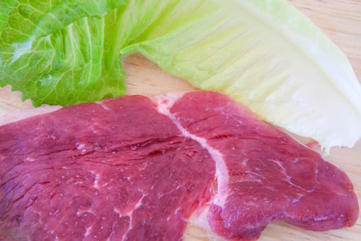 Steaks raw pork and lettuce on cutting board