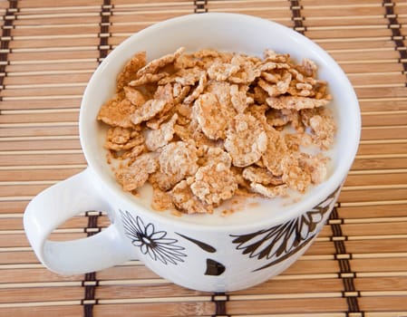 Breakfast bowl of cereal and milk on bamboo tablecloth