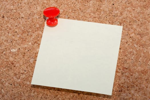 Red pin with note pinned to cork noticeboard