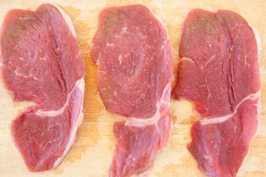 Three steaks raw salted pork on cutting board
