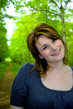 Portrait of a young woman walking on a path through the woods.