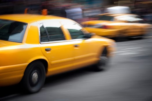 Abstract motion blur of a city street scene with a yellow taxi cabs speeding by.