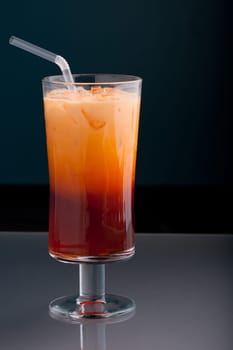 Thai iced tea served in a tall glass with cream and a straw.