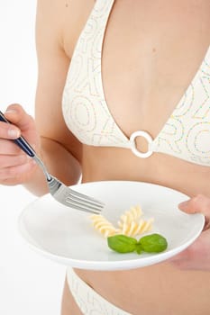 Young woman in bikini eating noodles from a small plate