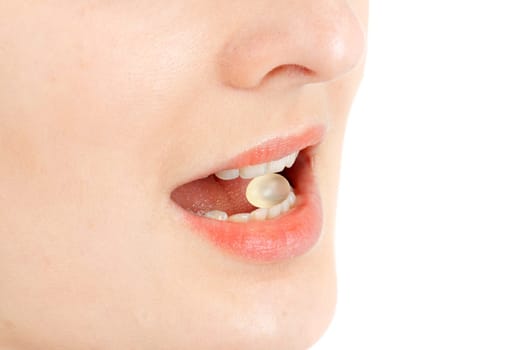Young woman with a pill between her teeth