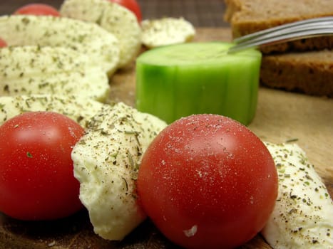 Sliced mozzarella with small tomatoes,cucumber slice and wholemeal bread