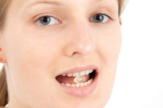 Young woman with a pill between her teeth