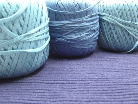 Three blue balls of wool arranged on blue blanket