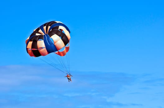 Photo of two people parasailing under blue sky.