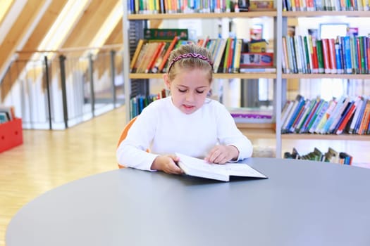 School girl reading a book in library