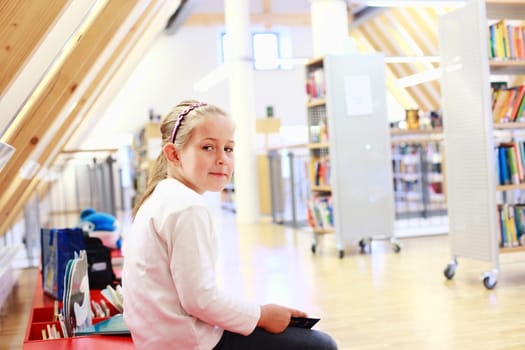 School girl reading a book in library