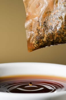 Close-up of a teacup with tea bags hanging and dripping over it