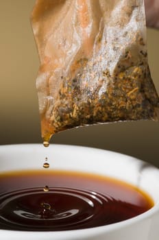 Close-up of a teacup with tea bags hanging and dripping over it