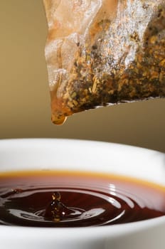 Close-up of a teacup with tea bags hanging and dripping over it