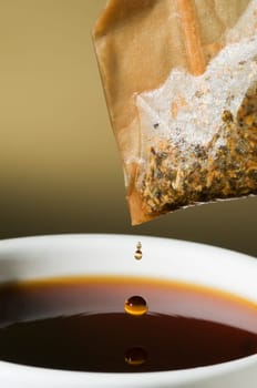 Close-up of a teacup with tea bags hanging and dripping over it