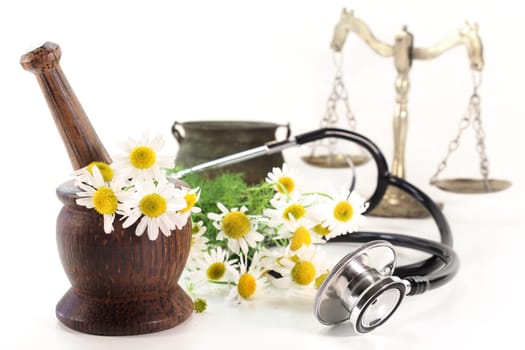 Stethoscope and chamomile against white background