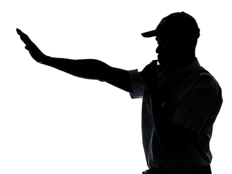 An afro American traffic cop making stop gesture while blowing whistle in studio on white isolated background