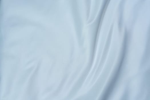 Close-up of soft white fabric with gentle folds creating a swirl pattern, perfect for backgrounds, textures, and design projects.