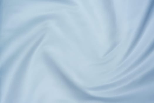 Close-up of soft white fabric with gentle folds creating a swirl pattern, perfect for backgrounds, textures, and design projects.