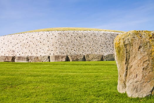 UNESCO World Heritage - Newgrange (Si An Bhru) neolithic passage tomb located on the river Boyne valley in Ireland. Side view with one of the surrounding standing stones.