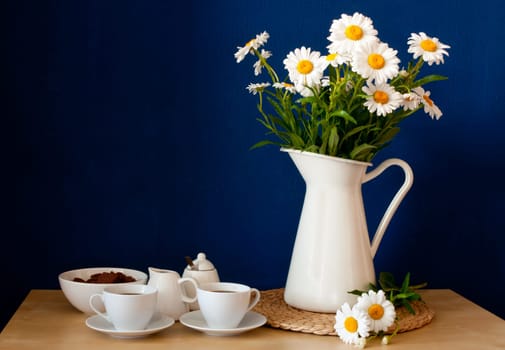 Coffee Mugs and Fresh Oxeye Daisies on wooden table in interior