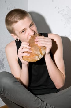 hungry teenager sitting in the corner and eat bread