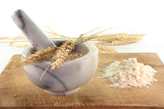 Grain in a mortar and ears of corn on a wooden board