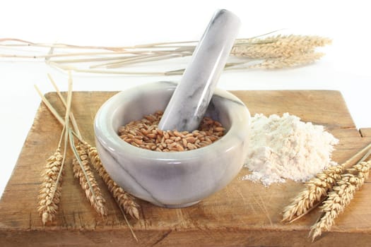 Grain in a mortar and ears of corn on a wooden board