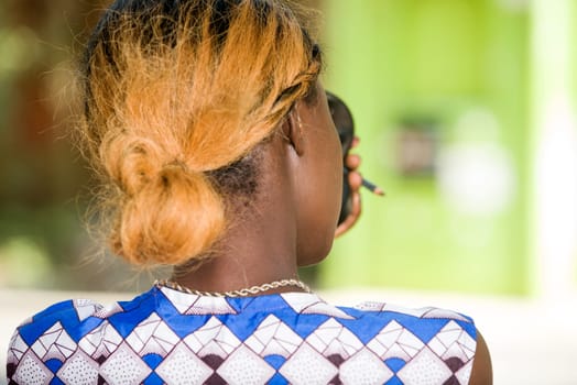 young woman standing outdoors doing make-up while giving back to the camera.