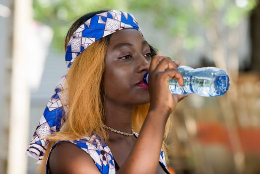 young woman standing outdoors go drinking water in a bottle.