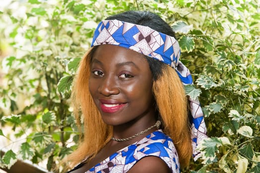 young african woman sitting in a park smiling at the camera.