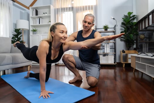 Happy active senior couple in sportswear being supportive and assist on yoga posture together at home. Healthy senior man and woman lifestyle with yoga exercise. Clout