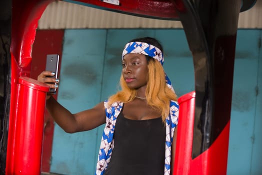 young woman standing in a booth watching mobile phone.