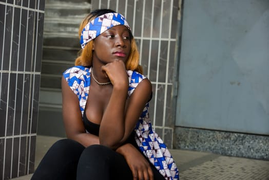 sad young woman in trouble lost in thought sitting outside hand on chin