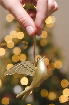 Decorating Christmas tree, holding Christmas toy in a hand. Holiday, Christmas and New Year family celebration concept.