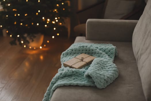 Christmas gift wrapped in craft paper under a tree. New Year card.