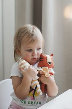 Little baby playing with funny small tiger toy, symbol of new 2022 in a sunny nursery