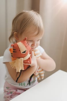 Little baby playing with funny small tiger toy, symbol of new 2022 in a sunny nursery