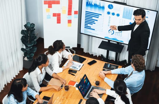 Wide top view of diverse group of business analyst team analyzing financial data report paper on meeting table. Chart and graph dashboard by business intelligence analysis. Meticulous